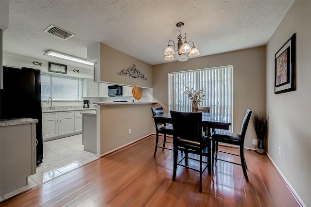 dining area featuring plenty of natural light, light hardwood / wood-style floors, and a textured ceiling