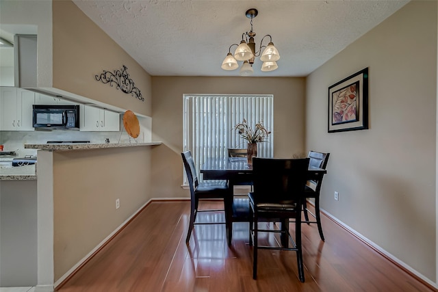 dining space with a notable chandelier, hardwood / wood-style flooring, and a textured ceiling