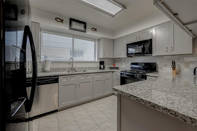 kitchen with sink, gray cabinetry, decorative backsplash, light tile patterned floors, and black appliances