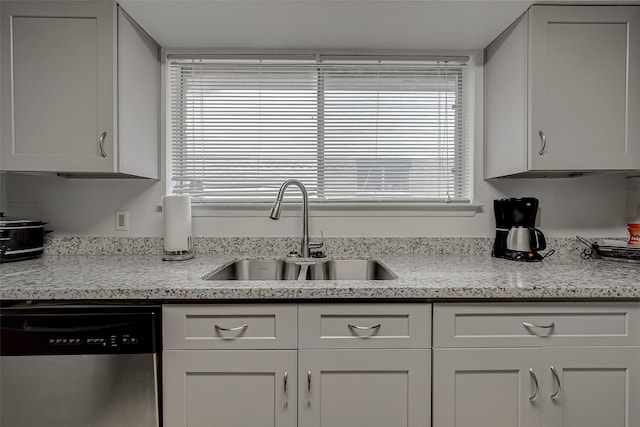 kitchen with dishwasher, sink, light stone countertops, and white cabinets