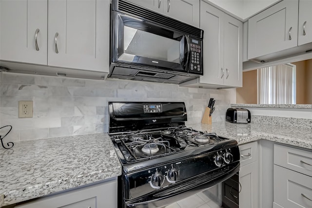 kitchen with white cabinetry, light stone counters, and black appliances