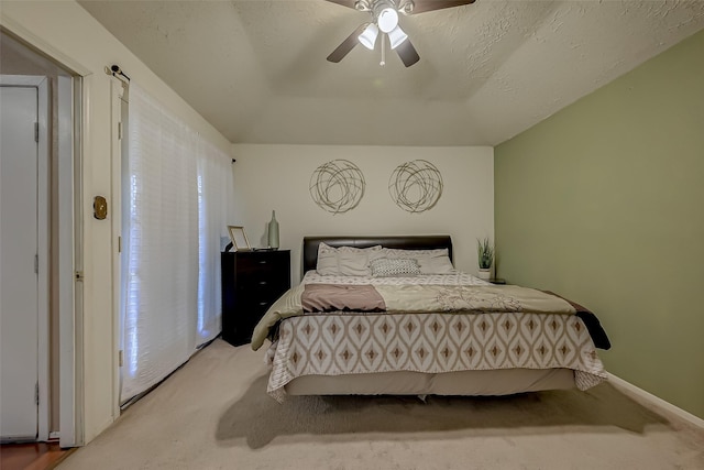 bedroom featuring ceiling fan, light colored carpet, and a textured ceiling