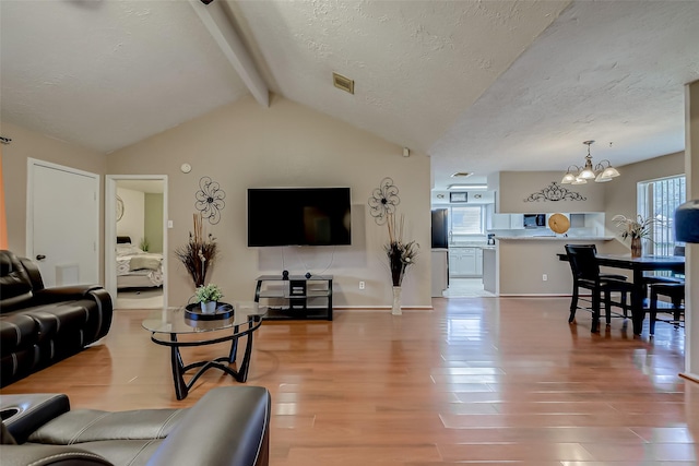 living room with wood-type flooring, lofted ceiling with beams, a chandelier, and a textured ceiling