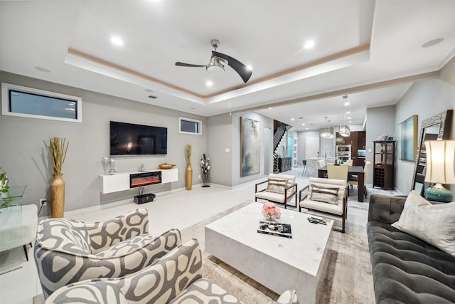 living room with sink, a tray ceiling, light tile patterned floors, and ceiling fan