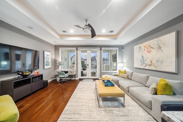 living room with ceiling fan, dark wood-type flooring, french doors, and a raised ceiling