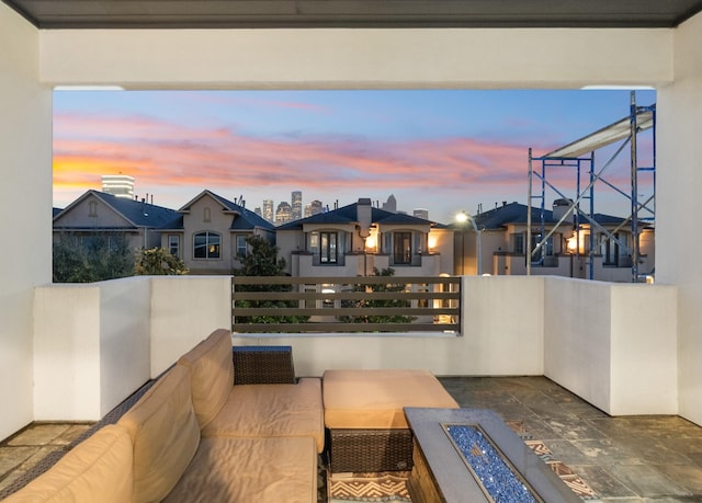 patio terrace at dusk featuring a balcony and an outdoor living space with a fire pit