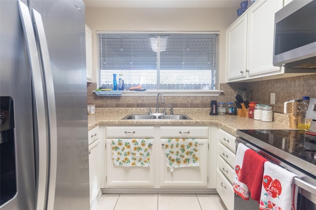 kitchen with sink, light tile patterned floors, appliances with stainless steel finishes, tasteful backsplash, and white cabinets