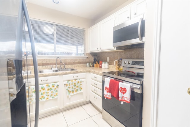 kitchen featuring light tile patterned floors, appliances with stainless steel finishes, sink, and white cabinets