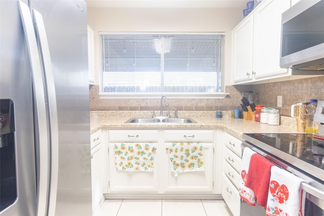 kitchen featuring sink, light tile patterned floors, appliances with stainless steel finishes, white cabinetry, and tasteful backsplash