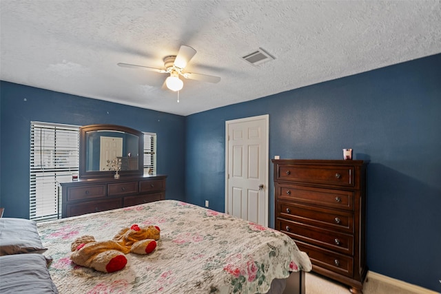 carpeted bedroom featuring ceiling fan and a textured ceiling