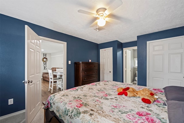 carpeted bedroom with ceiling fan, connected bathroom, and a textured ceiling