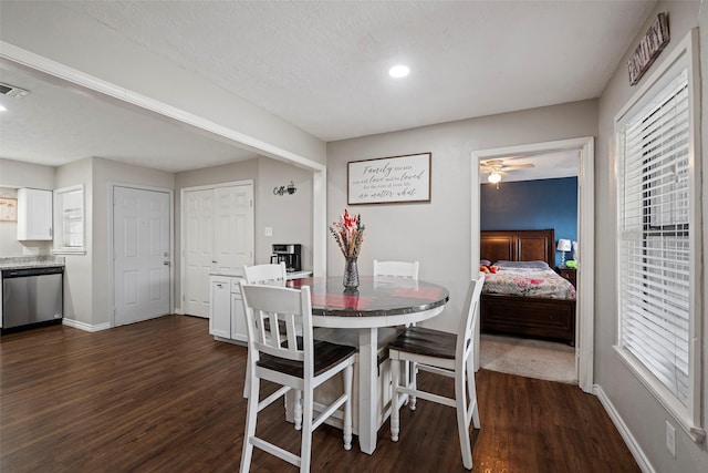 dining room with a wealth of natural light, a textured ceiling, and dark hardwood / wood-style flooring