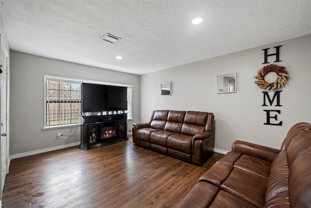 living room featuring dark wood-type flooring and a textured ceiling