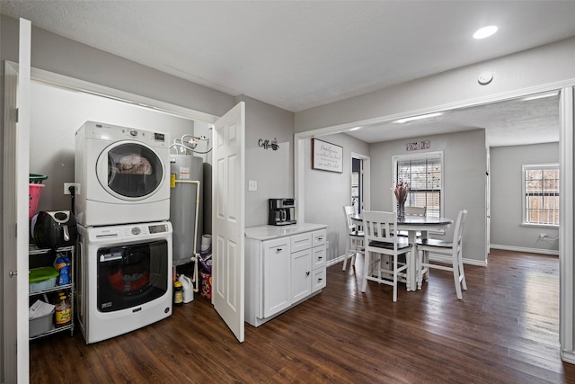 clothes washing area featuring stacked washer / dryer, dark wood-type flooring, and water heater