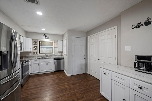 kitchen featuring light stone counters, stainless steel appliances, sink, and white cabinets