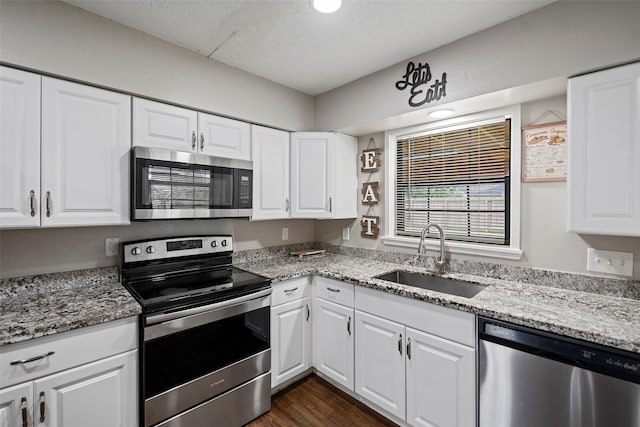 kitchen featuring appliances with stainless steel finishes, sink, white cabinets, and light stone counters