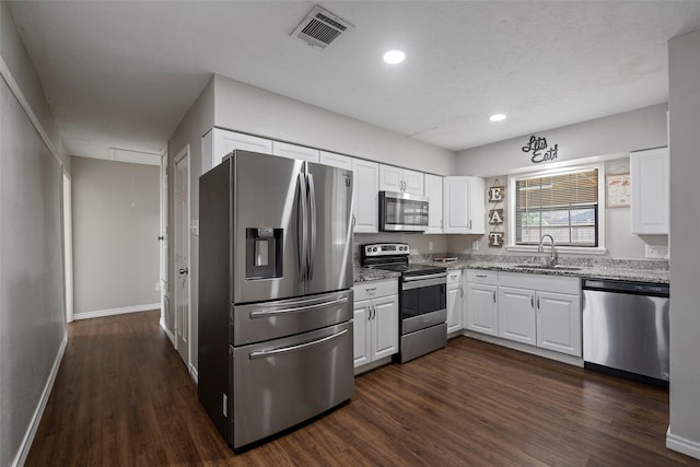 kitchen with dark hardwood / wood-style floors, sink, white cabinets, stainless steel appliances, and light stone countertops