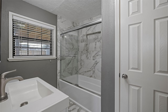 bathroom featuring enclosed tub / shower combo, sink, and a textured ceiling