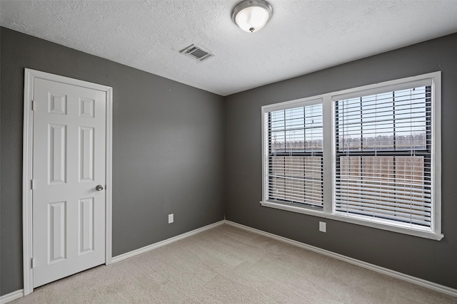 unfurnished room featuring light carpet and a textured ceiling