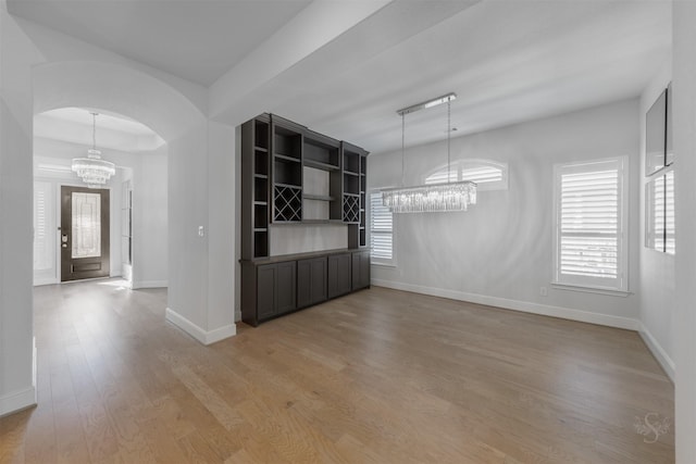 unfurnished dining area featuring an inviting chandelier and light hardwood / wood-style floors