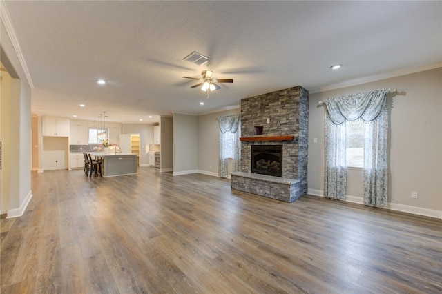 unfurnished living room with crown molding, dark wood-type flooring, ceiling fan, a fireplace, and a textured ceiling