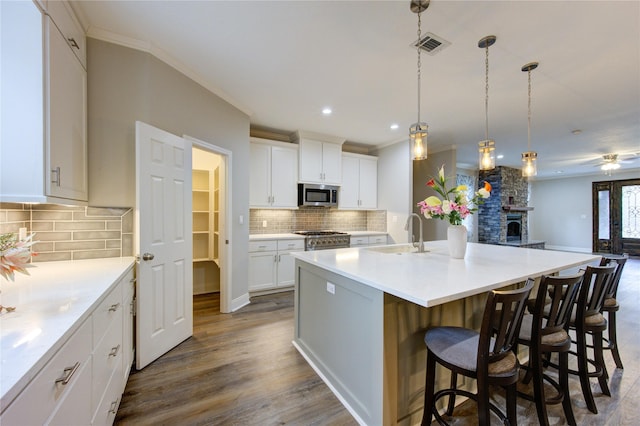 kitchen with an island with sink, appliances with stainless steel finishes, sink, and white cabinets