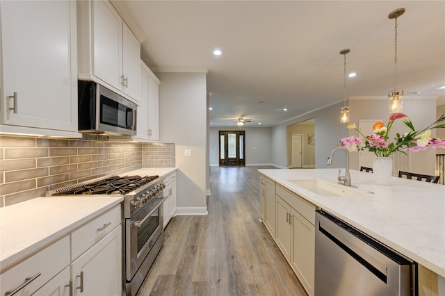 kitchen featuring appliances with stainless steel finishes, decorative light fixtures, tasteful backsplash, sink, and ornamental molding