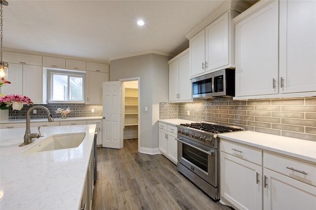 kitchen with pendant lighting, white cabinetry, sink, backsplash, and stainless steel appliances