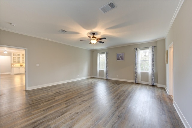 empty room featuring ornamental molding, dark hardwood / wood-style floors, a wealth of natural light, and ceiling fan