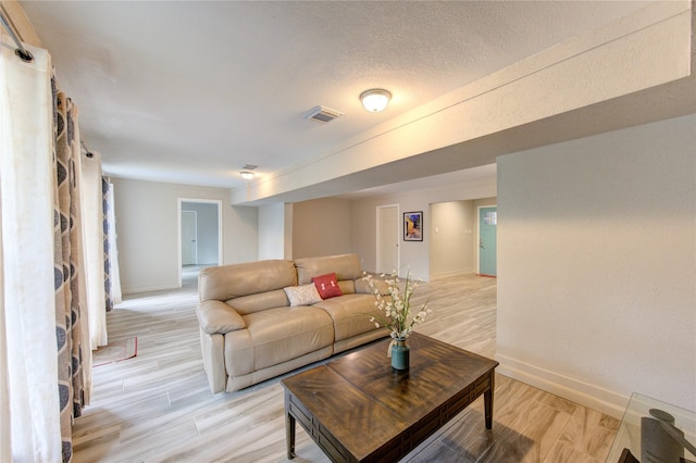 living room with a textured ceiling and light wood-type flooring