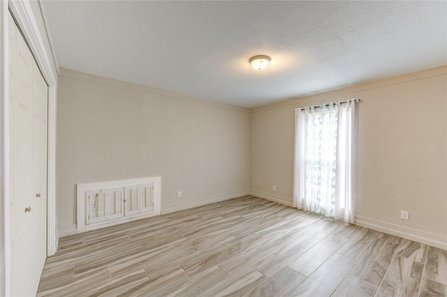 empty room with a textured ceiling and light hardwood / wood-style flooring