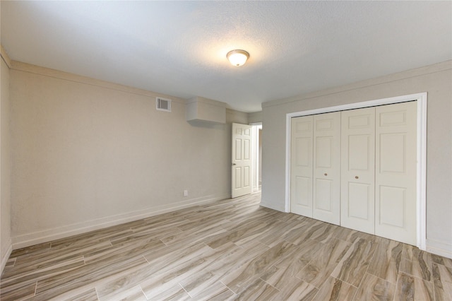 unfurnished bedroom featuring light hardwood / wood-style floors, a closet, and a textured ceiling