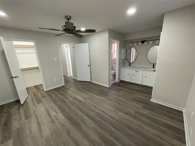 unfurnished bedroom with connected bathroom, a spacious closet, dark hardwood / wood-style floors, and ceiling fan