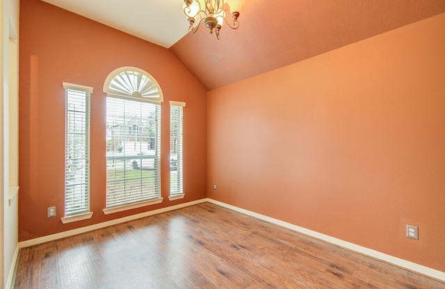 spare room with vaulted ceiling, wood-type flooring, and a chandelier