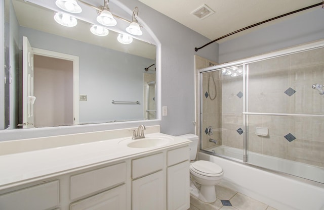 full bathroom with vanity, bath / shower combo with glass door, tile patterned floors, and toilet