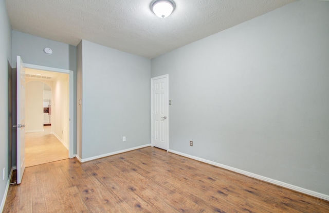 spare room with a textured ceiling and light wood-type flooring