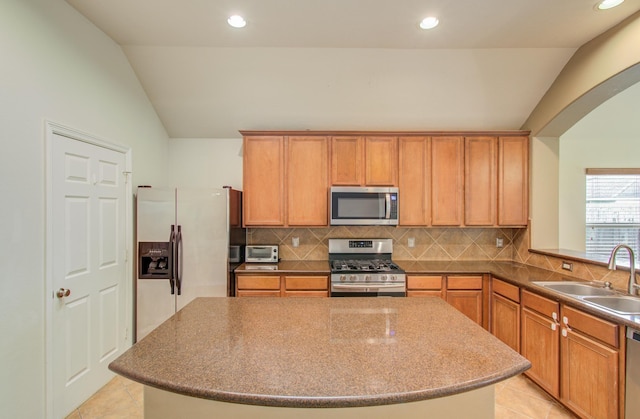 kitchen featuring tasteful backsplash, lofted ceiling, sink, a center island, and stainless steel appliances