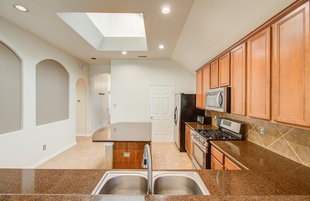 kitchen featuring sink, appliances with stainless steel finishes, kitchen peninsula, a kitchen island, and decorative backsplash