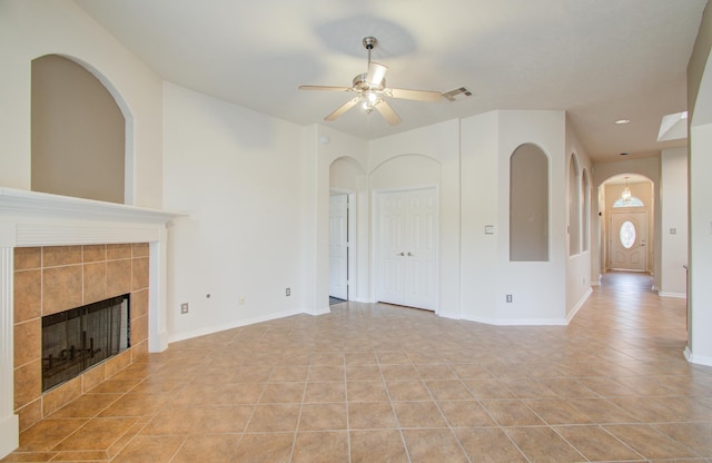 unfurnished living room with a tiled fireplace, light tile patterned floors, and ceiling fan