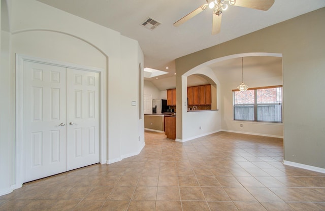 tiled empty room with vaulted ceiling and ceiling fan