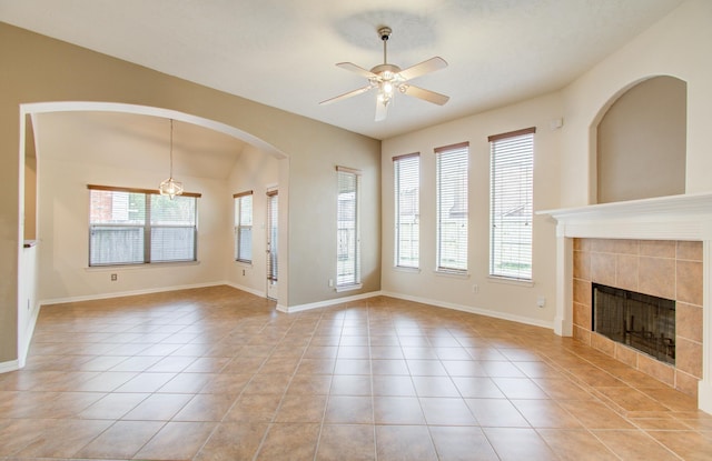 unfurnished living room featuring a tile fireplace, a wealth of natural light, light tile patterned floors, and ceiling fan