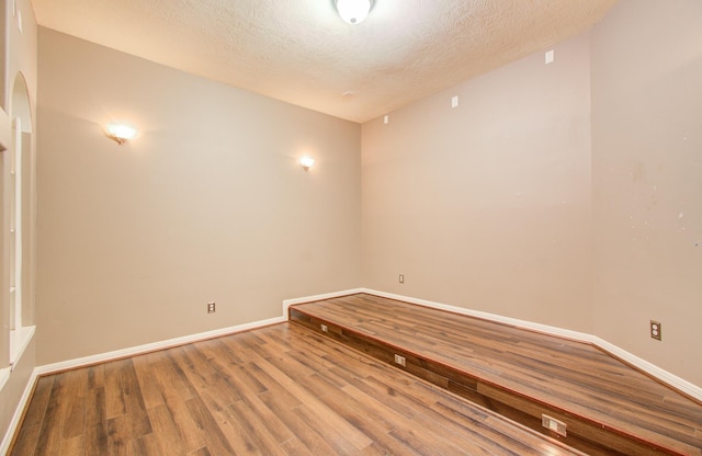 unfurnished room with wood-type flooring and a textured ceiling