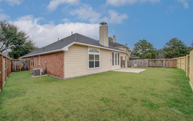 rear view of house featuring central AC unit, a yard, and a patio area