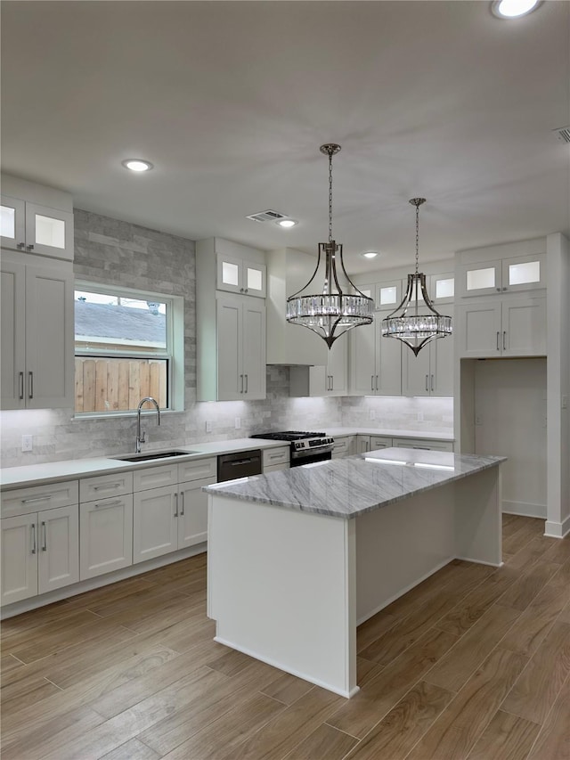 kitchen with sink, stainless steel range with gas cooktop, white cabinets, and a kitchen island