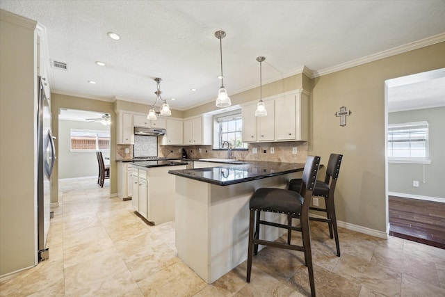 kitchen featuring a kitchen island, tasteful backsplash, white cabinetry, a kitchen bar, and hanging light fixtures