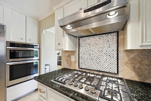 kitchen featuring appliances with stainless steel finishes, dark stone countertops, tasteful backsplash, ventilation hood, and white cabinets