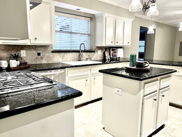 kitchen with decorative light fixtures, sink, white cabinets, ornamental molding, and a center island