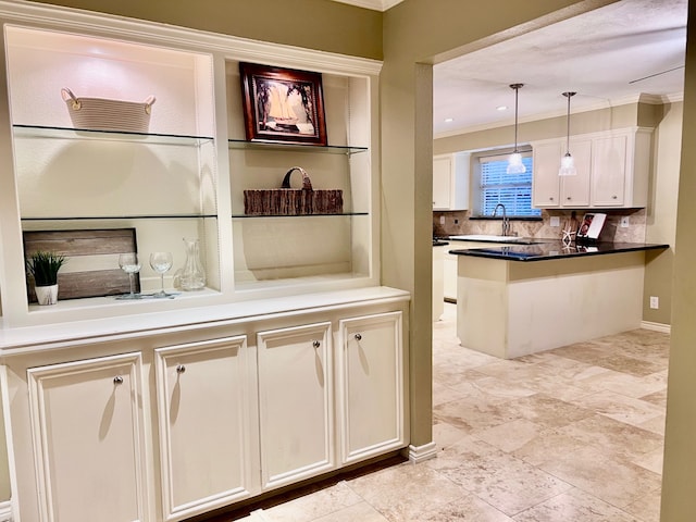 kitchen with sink, white cabinetry, tasteful backsplash, crown molding, and decorative light fixtures