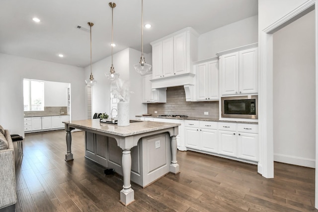 kitchen with white cabinetry, black microwave, pendant lighting, and a kitchen bar