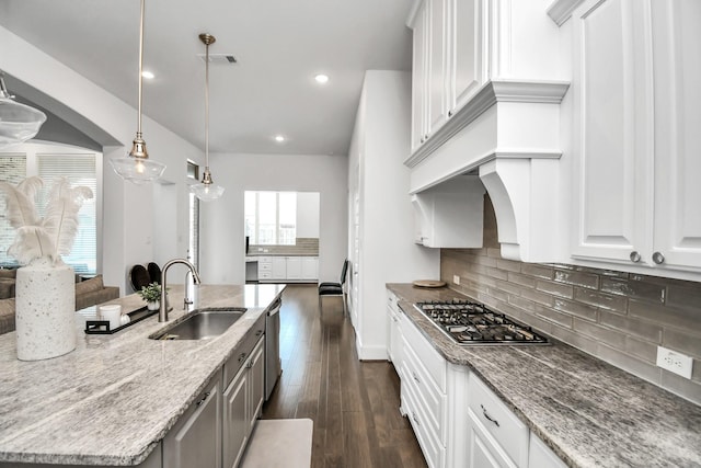 kitchen with dark wood-type flooring, sink, white cabinetry, pendant lighting, and light stone countertops